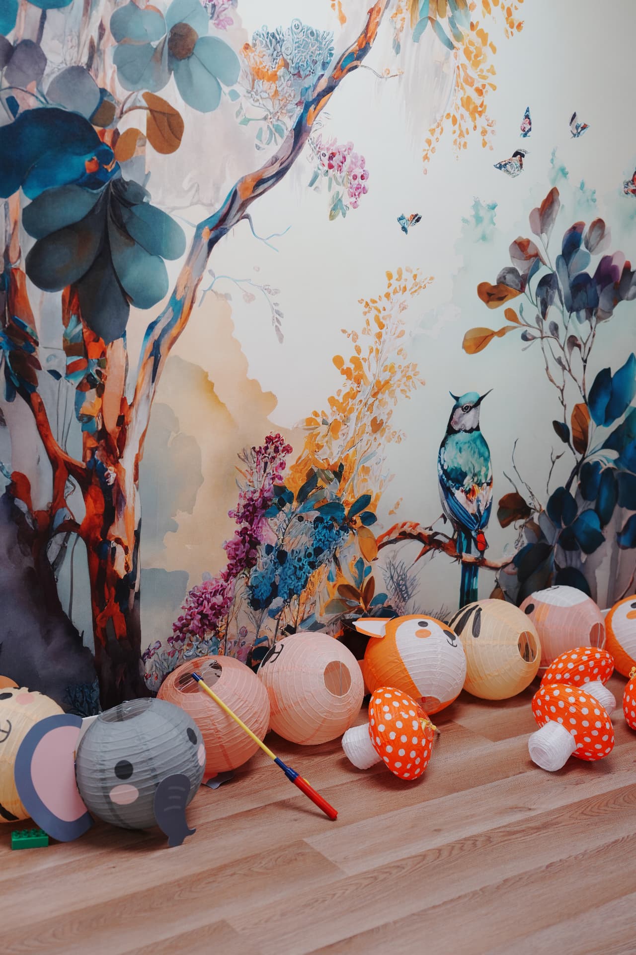Moon Exploration family event: animal-shaped paper lanterns on a table beneath a colorful bird and floral backdrop.